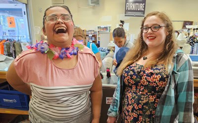 Denise and KK laughing behind the counter at the thrift shop.